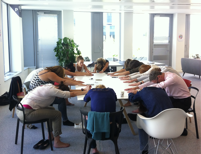 Groupe de personne faisant du yoga autour d'une table pendant la semaine de qualité de vie au travail